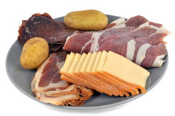 Assiette pour une raclette avec de la charcuterie, du fromage et des pommes de terre
