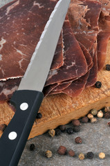 Couteau posé sur des tranches de viande des Grisons avec des baies