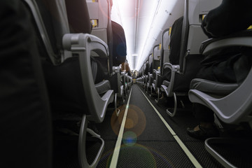 Inside the airplane : Modern interior of aircraft. Black seats inside airplane with flare light.
Symmetric vanishing row of seats inside air transport. Economy class of flight.