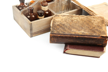Vintage bottles in wooden box and old books isolated on white
