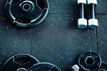 Weight plates and dumbbells on floor in gym