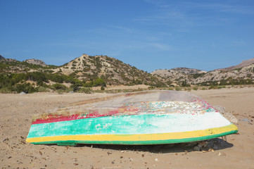 Turned old wooden painted fishing boat on sand of Tsambika beach, Rhodes Island, Greece.
