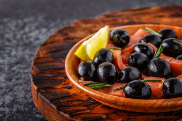 Salmon with olives and lime on a wooden board.