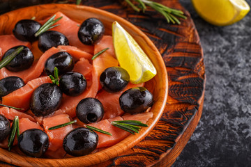 Salmon with olives and lime on a wooden board.