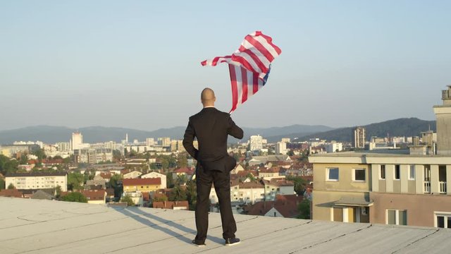 Close up businessman looking proudly down on his hometown holding American flag