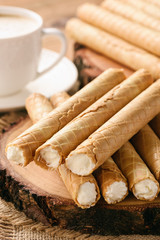 Rolled wafers with whipped cream filling on wooden background.