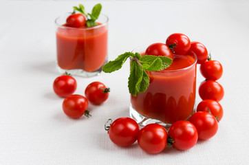 Tomatoes and juice in a glass on a light background