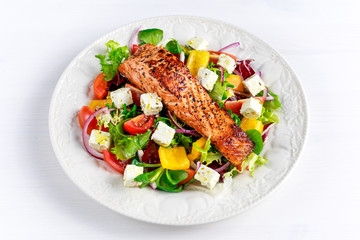 Fried Salmon steak with fresh vegetables salad, feta cheese. concept healthy food.