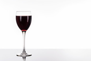 Ein Glas Rotwein auf spiegeldem Tisch vor hellem Hintergrund