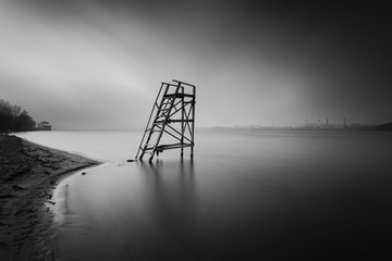 Lifeguard tower on the late autumn beach. Minimalist landscape with foggy river on long exposure. Kiev. Ukraine.