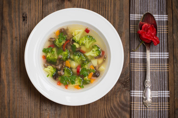Vegetable soup with broccoli, mushrooms and herbs. Wooden background. Top view. Close-up