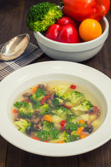 Vegetable soup with broccoli, mushrooms and herbs. Wooden background. Top view. Close-up