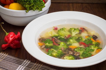 Vegetable soup with broccoli, mushrooms and herbs. Wooden background. Top view. Close-up