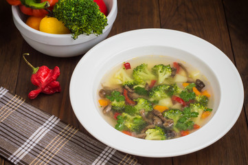 Vegetable soup with broccoli, mushrooms and herbs. Wooden background. Top view. Close-up