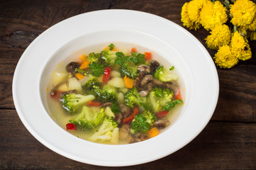 Vegetable soup with broccoli, mushrooms and herbs. Wooden background. Top view. Close-up