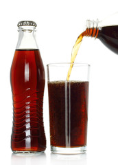 Bottle of cola with cola pouring into glass on white background.