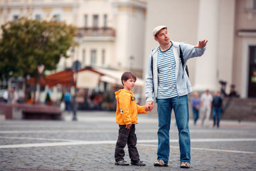 Father and son walking outdoors in city - obrazy, fototapety, plakaty