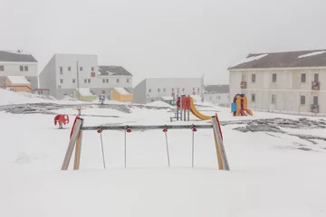 Fototapete Arktis Harsh greenlandic childhood,playground covered in snow and ice i