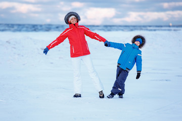Cute little boy and his mother on icy beach