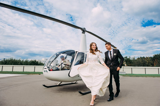Happy beautiful newlyweds near the helicopter