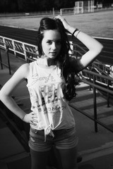 Girl having fun outdoor. Pretty girl sitting at school stadium.