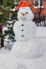 Snowman in a red cap on a snow