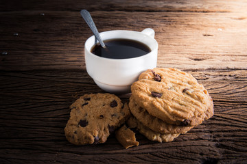 Coffee cup with chocolate cookie on dark wooden