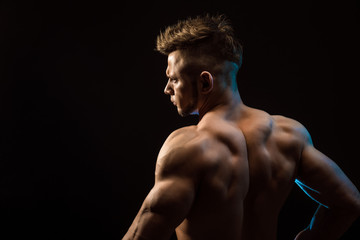 Strong Athletic Fitness Man posing back muscles, triceps, latissimus over black background