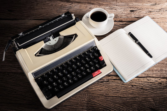 Vintage typewriter and a blank notebook , pen and coffee cup
