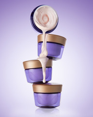 Four jars of cosmetic, moisturizing, anti-aging cream stand on each other on the gradient purple background