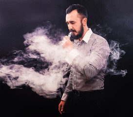 Men with beard vaping and releases a cloud of vapor.