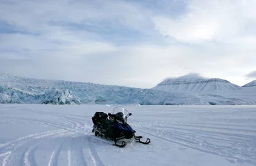 Foto op Canvas De sneeuwscooter op de bevroren fjord. Deze foto toont de sneeuwscooter op het ijs van Billefjord bij Pyramiden en gletsjer Nordenskiöldbreen op de achtergrond (Svalbard). © Anna Silanteva