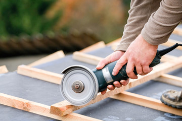 construction worker on a renovation roof covering it with tiles