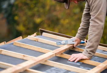 construction worker on a renovation roof covering it with tiles