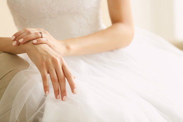 Bride in beautiful wedding gown sitting on sofa