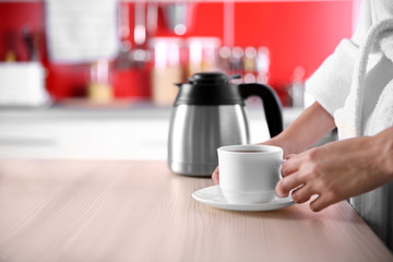 Woman with cup of coffee in kitchen
