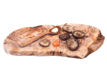 Shiitake marinated mushrooms with wooden spoon on olive wood cutting board isolated on white background