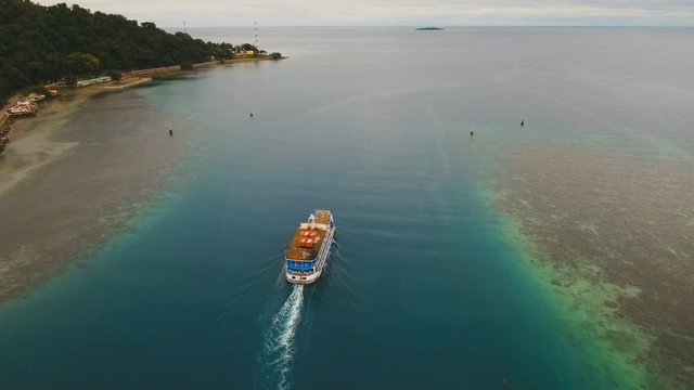 Aerial view passenger ferry floats in the blue sea.Asian passenger boat floating in the ocean.Philippines, Camiguin. Passenger ferry boat Camiguin to Mindanao. 4K video.Travel concept. Aerial footage.