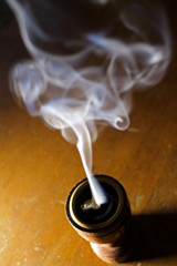 Incense burner against dark background swirling smoke natural wood