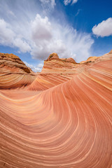 The Wave - Swirling sandstone waves and rolling clouds at The Wave, a dramatic and colorful erosional sandstone rock formation located in North Coyote Buttes area at Arizona-Utah border. 