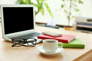 Workplace with laptop and cup of coffee, close up