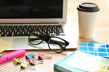 Workplace with laptop, eyeglasses and cup of coffee, close up