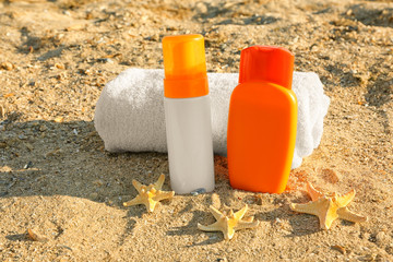 Fototapeta na wymiar Towel, starfish and sunscreen cream on sea sand