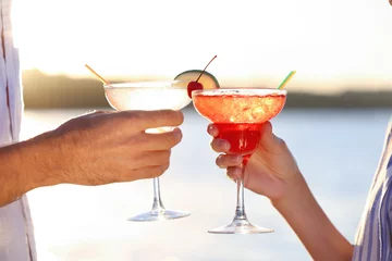 Photo sur Plexiglas Cocktail Male and female hands holding glasses with margarita cocktail on blurred background
