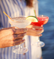 Fototapeta premium Male hand holding glass with margarita cocktail on blurred background, close up