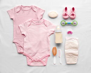 Baby care accessories and clothing on light background, top view