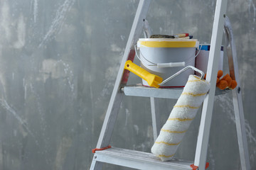 Ladder and set of tools for repair near grunge wall, closeup