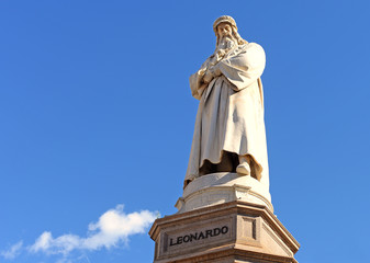 statue of leonardo da vinci against blue sky with a fluffly white cloud on e bright spring day in...