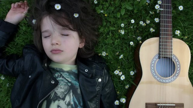 4k Shot of a Cute Child Outside Sleeping with his Guitar on the Grass