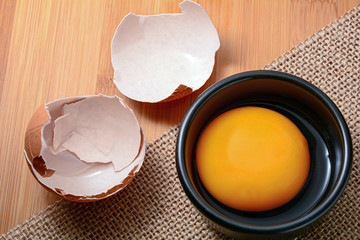 egg yolk in black bowl and on wooden table